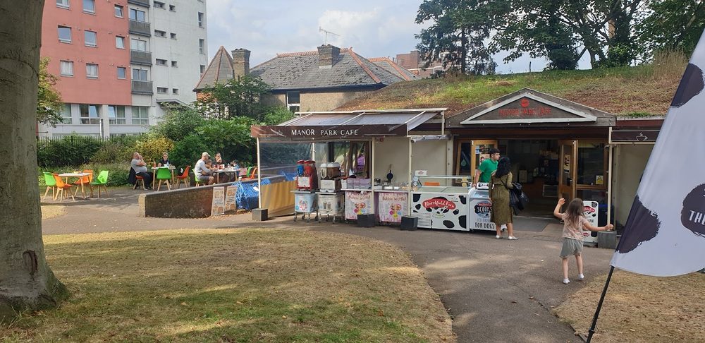 The cafe building seen from across the park, with its terrace, flags and outdoor seating