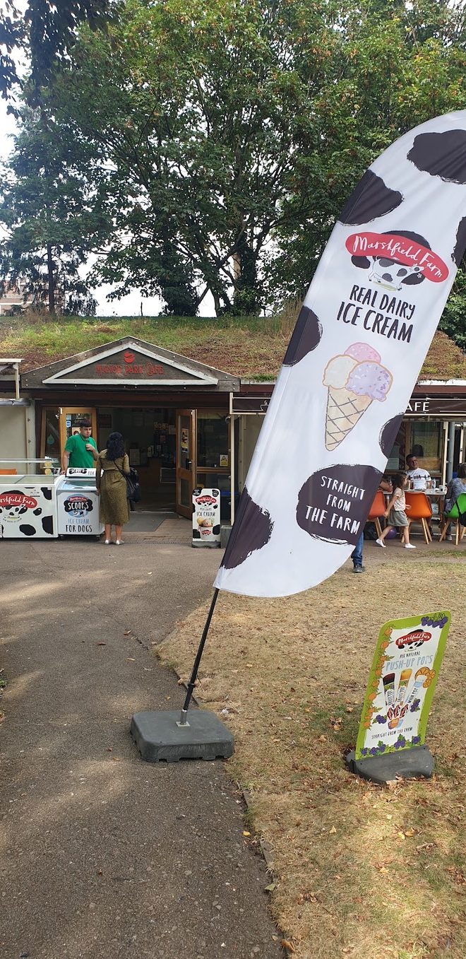 A tall cow-print ice cream feather flag standing in front of the cafe kiosk