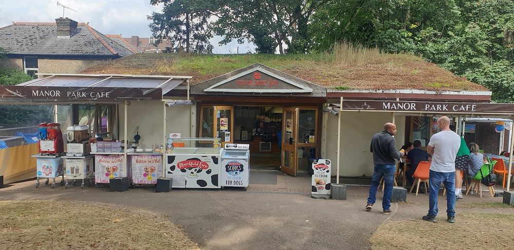 The Manor Park Cafe kiosk in Manor Park, Sutton, with its terrace and a few people outside