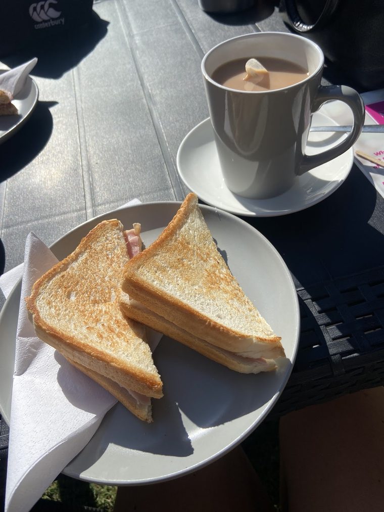 A toasted cheese sandwich cut into triangles beside a mug of milky tea